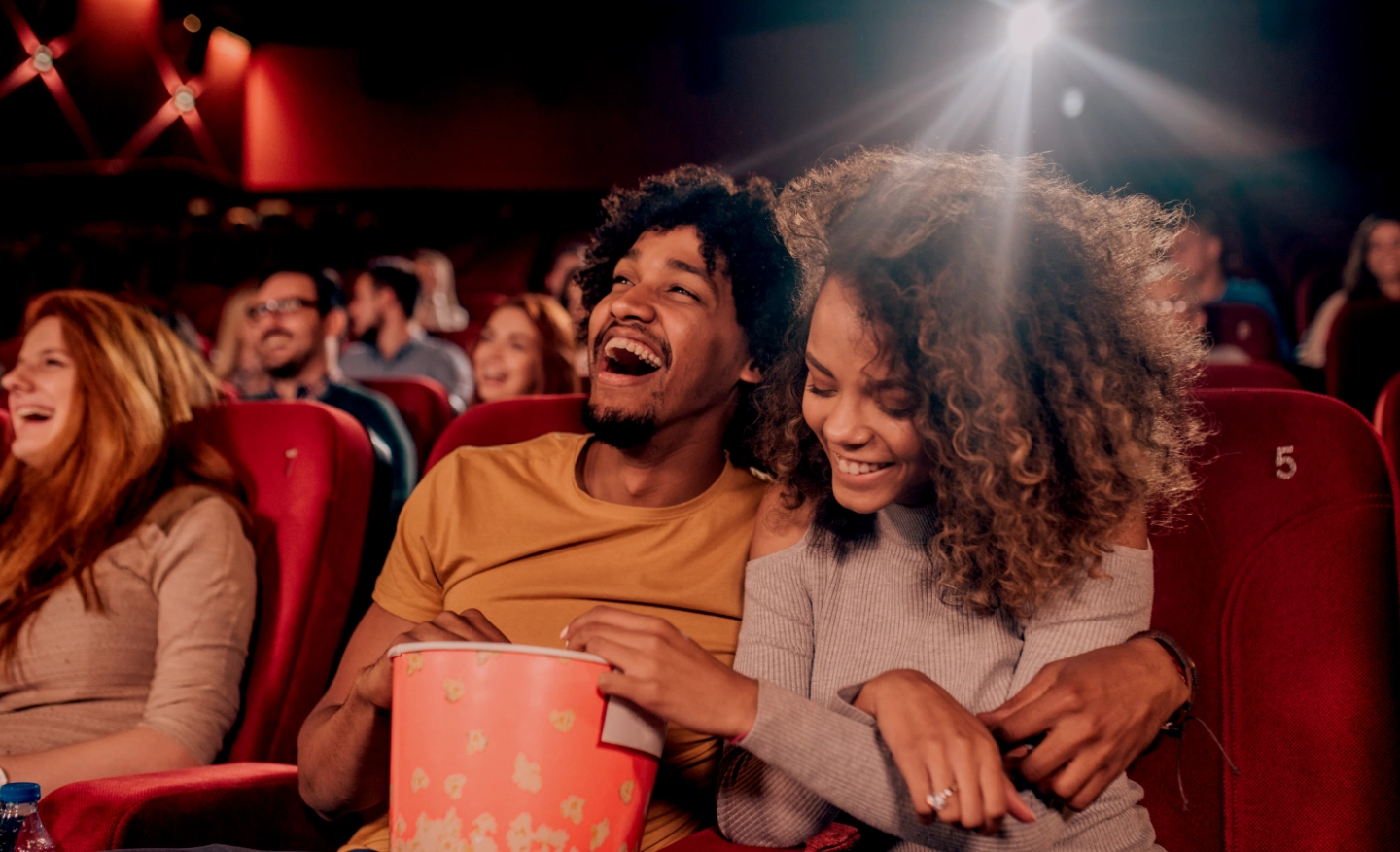 #BradescoAcessível #Pratodomundover Vemos um casal sorrindo enquanto assiste um filme no cinema. Vemos também grafismos vermelhos em volta da imagem.