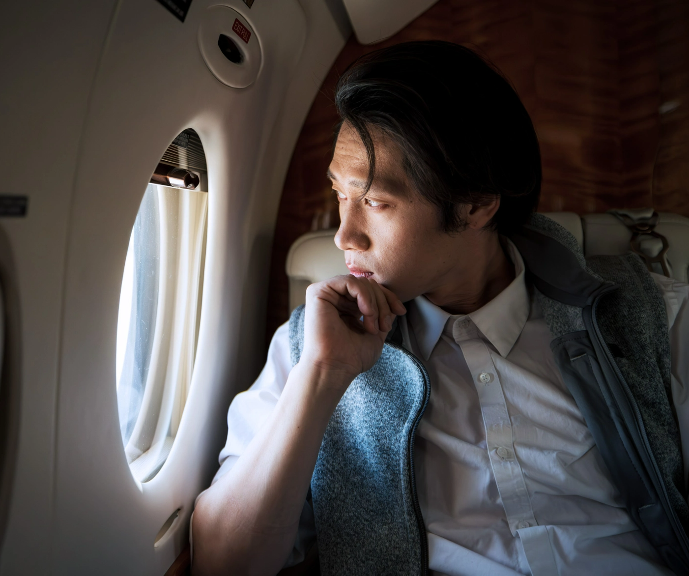 #BradescoAcessivel #ParaTodoMundoVer: um homem sentado olha para a janela do seu
      jato particular em voo.
      