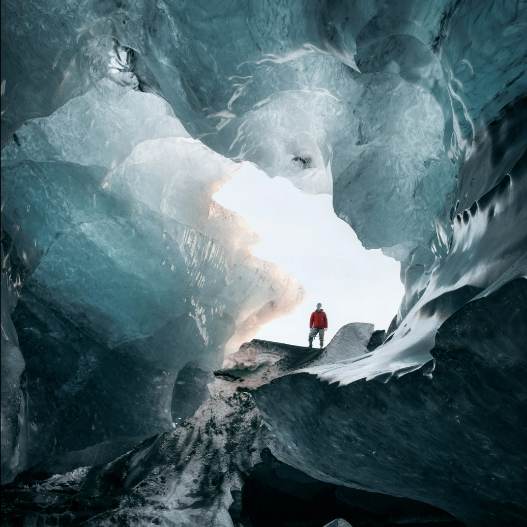 #BradescoAcessivel #ParaTodoMundoVer: De dentro de uma caverna de gelo, vemos a
      silhueta de um homem que está entrando na caverna e fazendo uma pose de
      aventureiro.