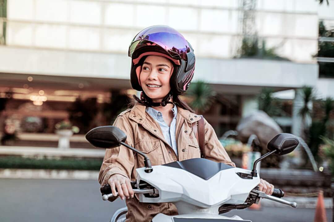 Menina sorrindo pilotando uma moto